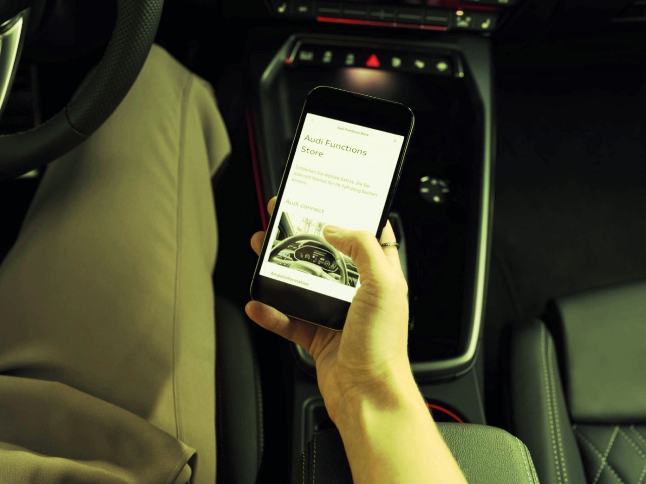 Detail of a hand holding a smartphone inside a car. 